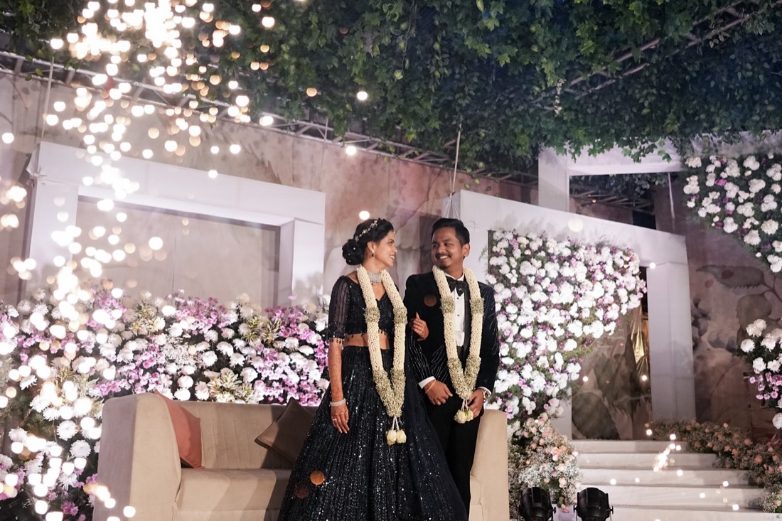 Couple at a floral reception stage with fairy lights by SGR Decorators